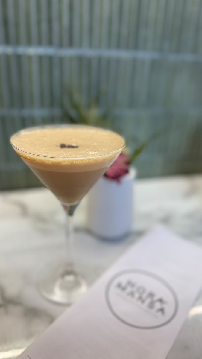 Amarula Espresso Martini in a martini glass, beside the Hora Mansa menu on the marble counter.