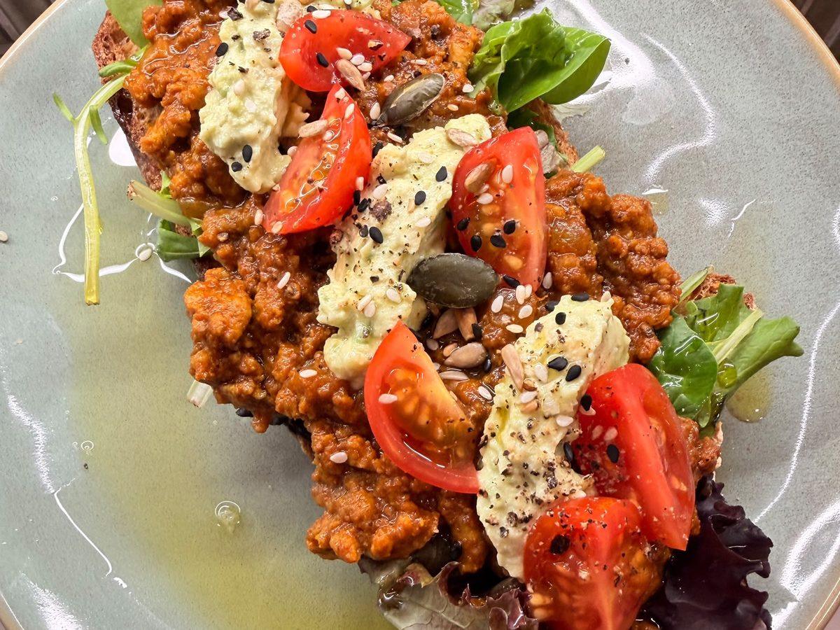 Boertjie — aromatic mince topped with creamy avocado, cherry tomatoes, fresh greens and seeds on toasted artisan bread. / Boertjie — carne moída aromática com abacate cremoso, tomate cereja, folhas verdes e sementes sobre pão artesanal tostado.