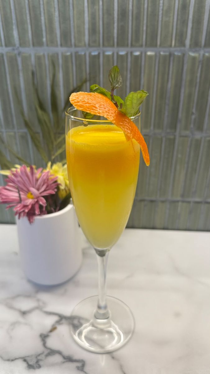 Mimosa with fresh orange juice, mint and an orange twist, against the sage tiles of Hora Mansa.
