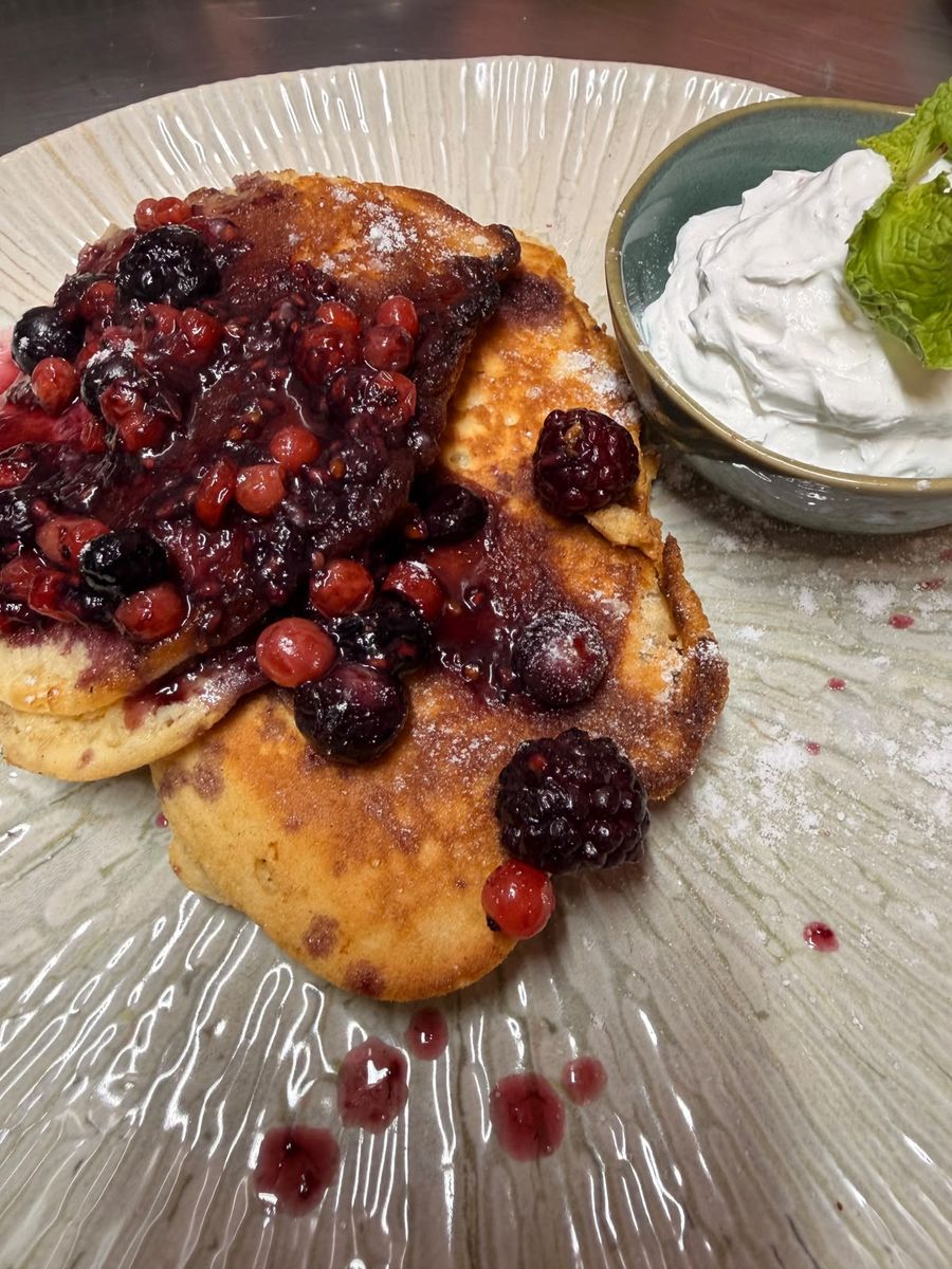 Sweet American pancakes with berry compote, icing sugar and whipped Chantilly cream.